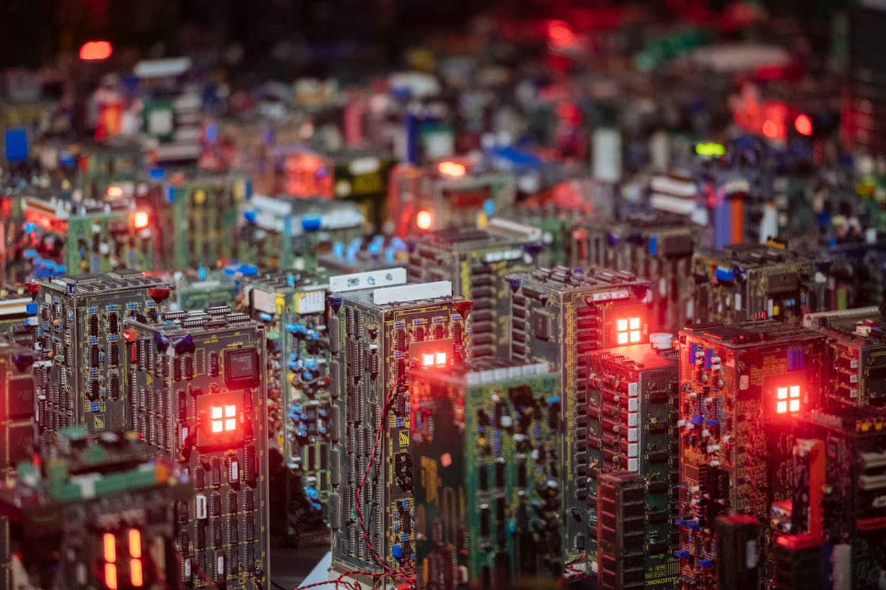 services-03 Close-up view of illuminated circuit boards resembling a cityscape, showcasing intricate electronic design.