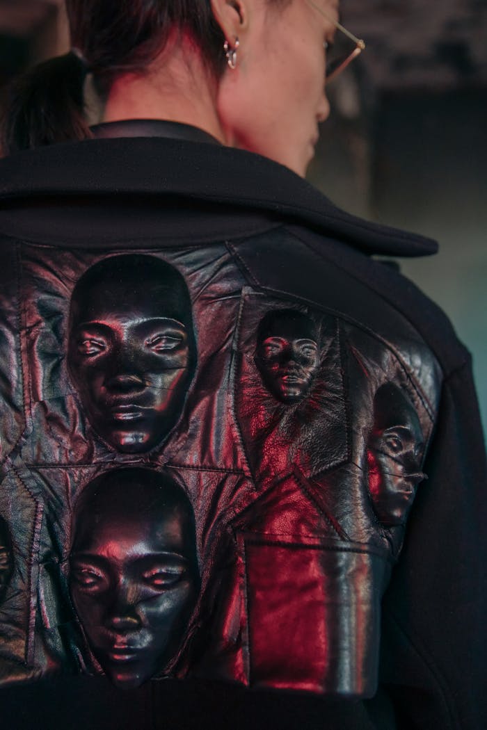 Man in contemporary leather jacket with artistic face designs, exuding a cyberpunk fashion vibe.